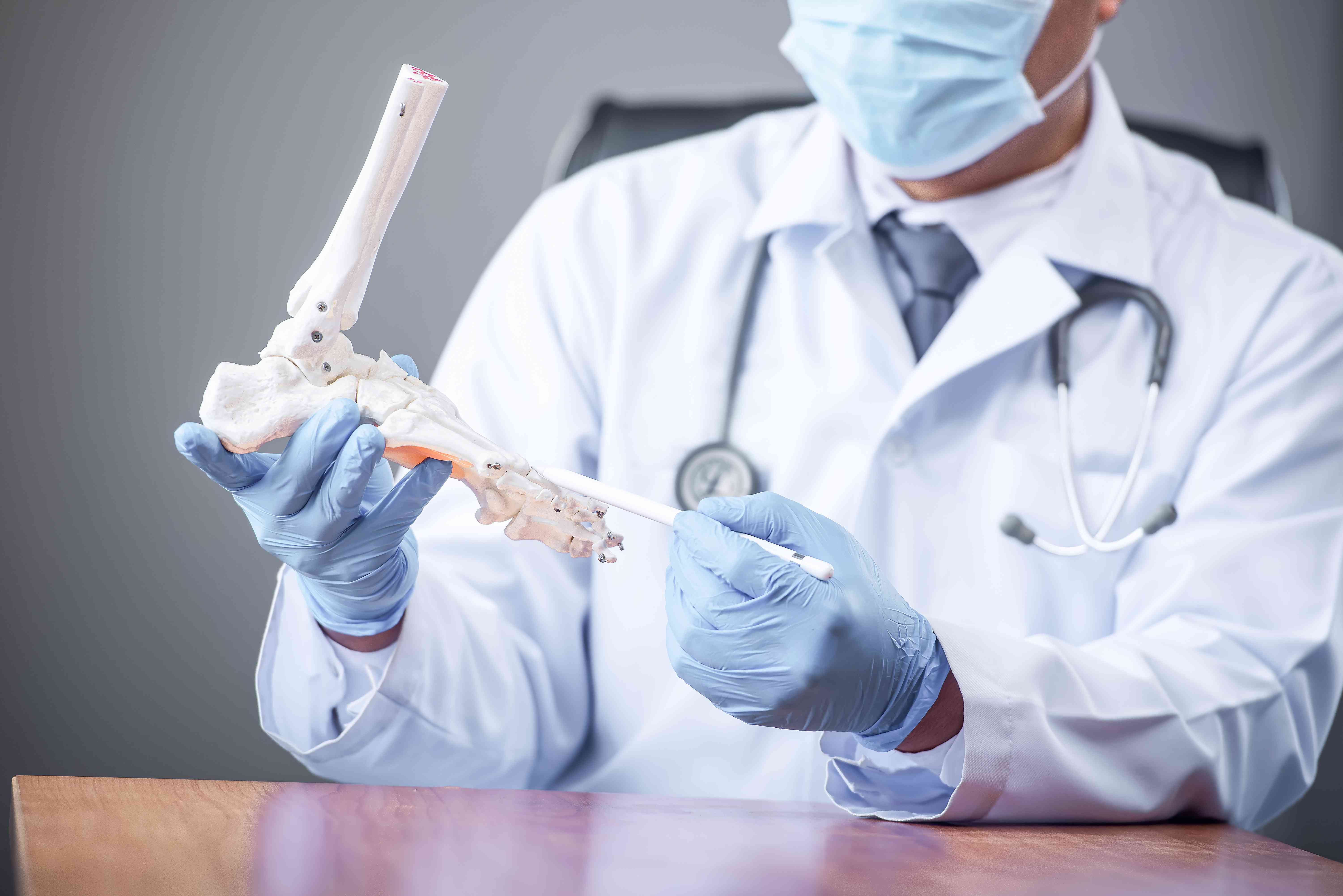 orthopedic-doctor-looking-fake-ankle-bone-male-doctors-orthopedic-wears-medical-masks (1)-compressed